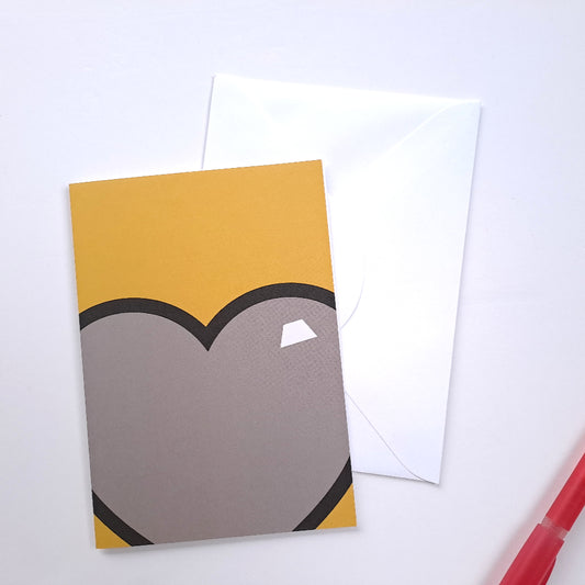 yellow greeting card with grey love heart against white background